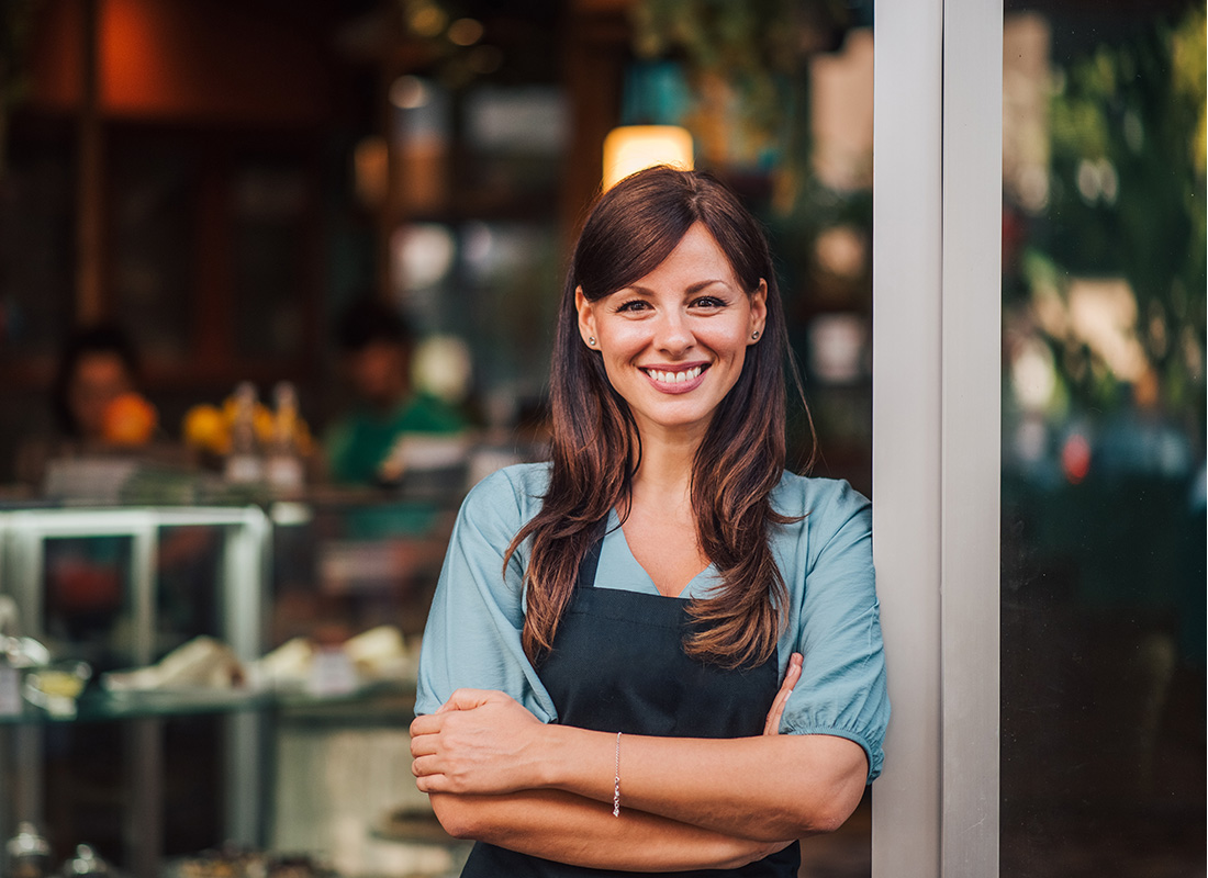 Insurance by Industry - Portrait of a Smiling Young Female Small Business Owner Standing Outside her Main Town Shop with her Arms Folded